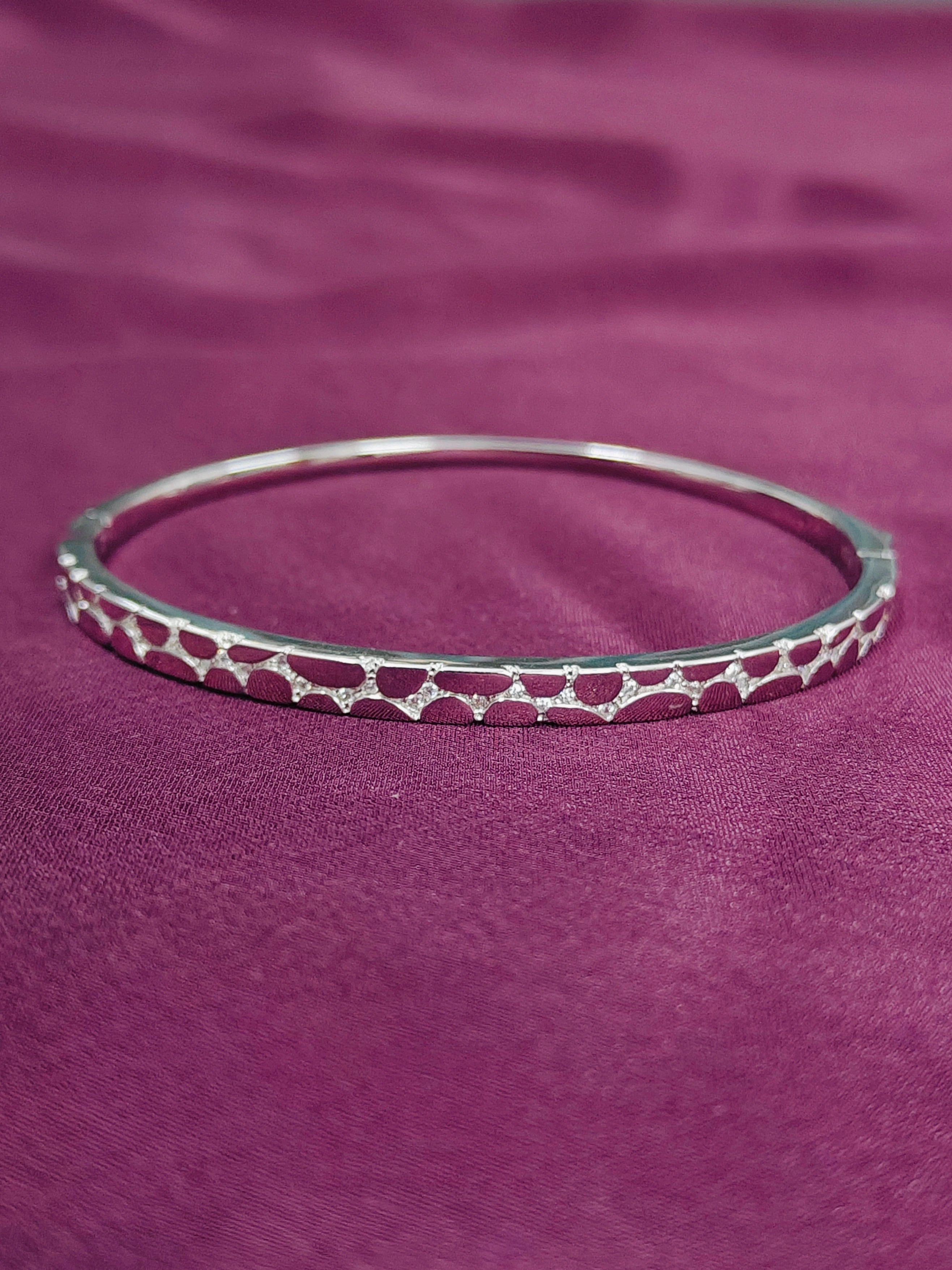 Silver bracelet with red pattern on a purple fabric background